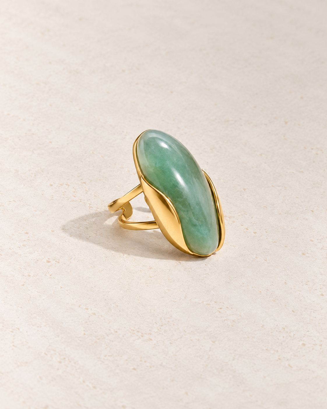 Anillo Isabella con piedra verde sobre cemento blanco