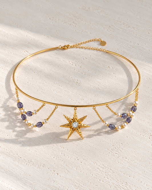 Choker Aurore dorado con estrella y perlas sobre cemento blanco